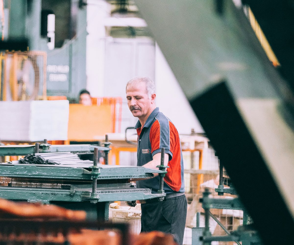 An experienced machine operator working at a press on a factory floor